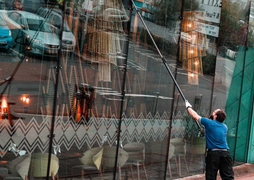 Cleaning the glass front of a commercial building with a water-fed pole