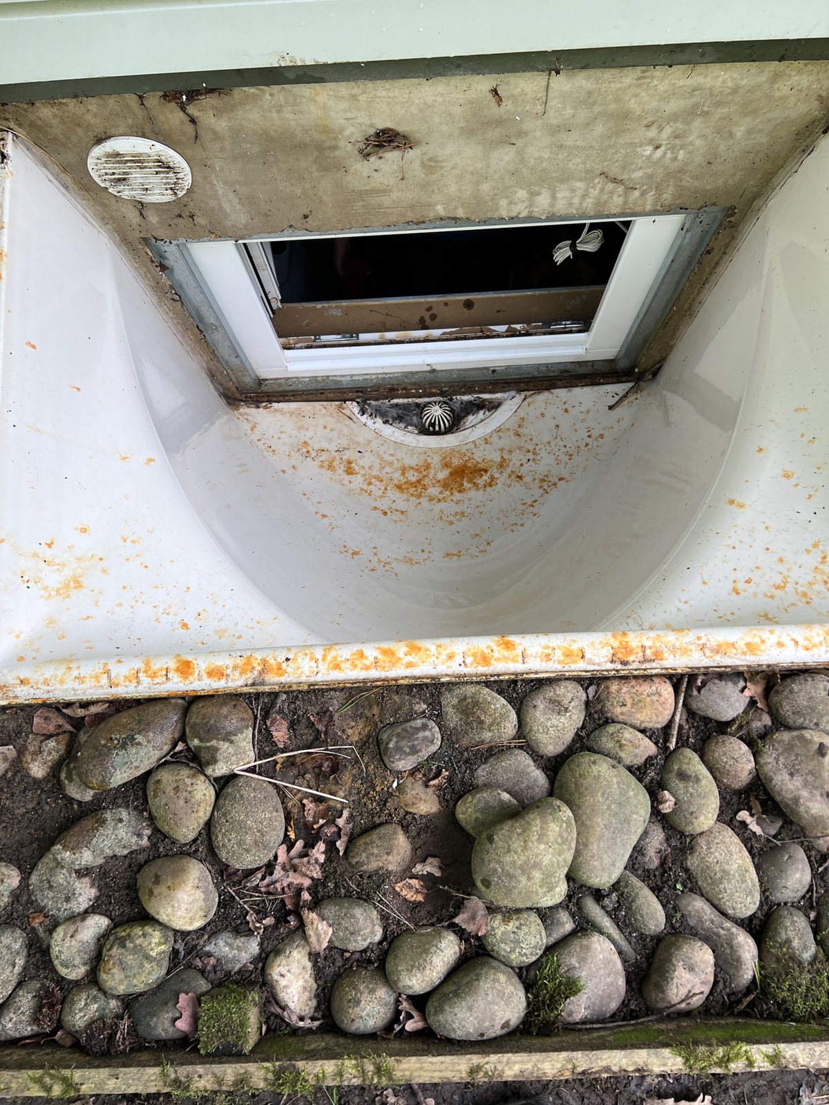 Basement lightwell cleaned in Godalming Surrey — white render walls and clear cobble base