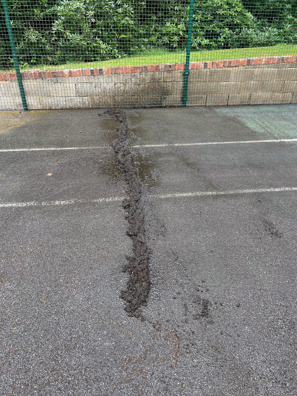 Tennis court with algae and dark patches before cleaning in Crawley Down West Sussex
