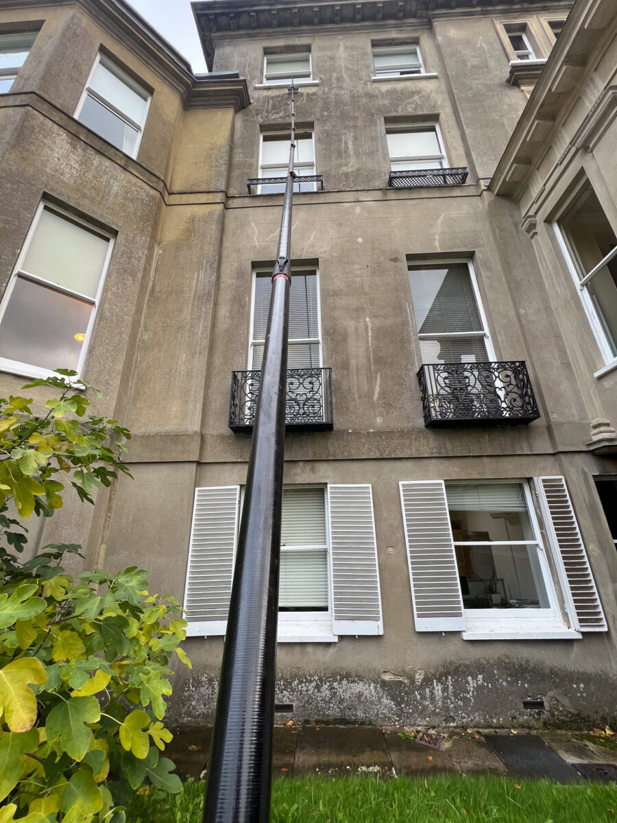 Water-fed pole cleaning fourth-floor sash windows from the ground, Gomshall near Guildford