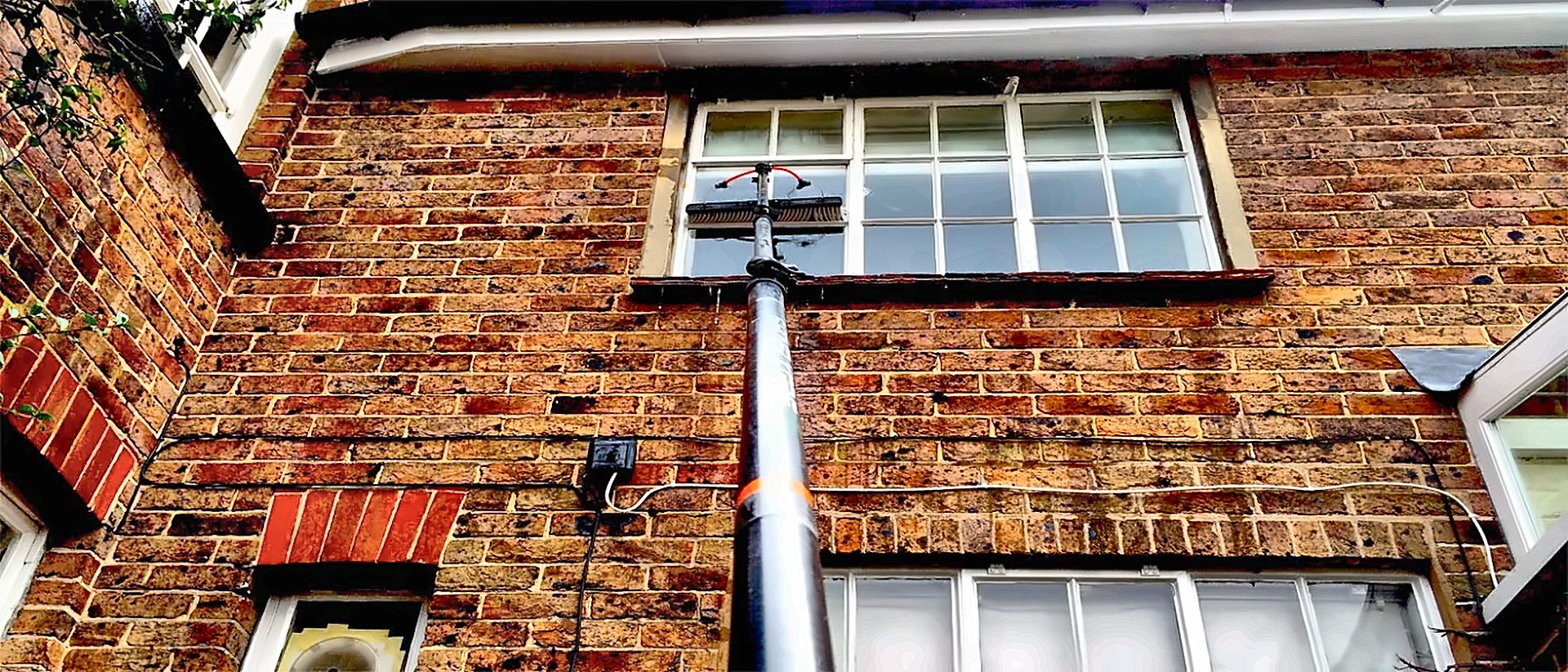 Water-fed pole cleaning an upstairs sash window in Surrey